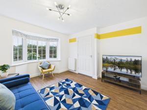 a living room with a blue couch and a tv at Spacious 5 Bed Contractor Hub 3 Baths Corby in Corby