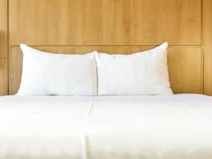 a bed with white pillows on top of it at Ibis Girona in Girona