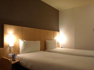 a hotel room with a large bed with two lamps at Ibis Girona in Girona +93 photos
