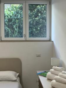 a bedroom with two windows and a table with towels at Central Apartment in Matera