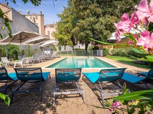 a swimming pool with chairs and an umbrella at ibis Styles Macon Centre in Mâcon