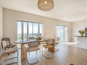 ein Esszimmer mit Tisch und Stühlen und Fenstern in der Unterkunft 4 Bed in Aberdovey 87586 in Aberdyfi