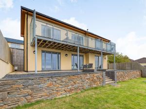 ein Haus an einer Steinmauer mit einem Balkon in der Unterkunft 4 Bed in Aberdovey 87586 in Aberdyfi
