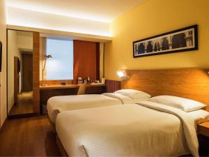 a hotel room with two beds and a window at ibis Bengaluru Hosur Road - An Accor Brand in Bengaluru