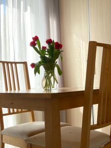 un vase de roses rouges assis sur une table en bois dans l'établissement Willa Wiosenna, à Kołobrzeg
