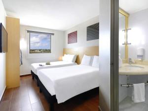 a hotel room with a white bed and a sink at Ibis Cancun Centro in Cancún +41 photos