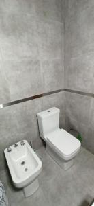 a bathroom with a white toilet and a sink at La Cabaña de Lali in Monte Hermoso +10 photos