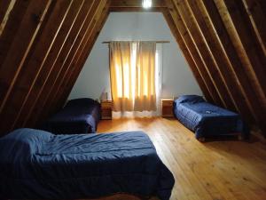 an attic room with two beds and a window at La Cabaña de Lali in Monte Hermoso