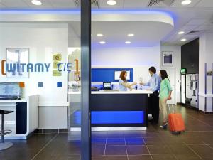 three people standing at a counter in an office at ibis budget Warszawa West Station in Warsaw