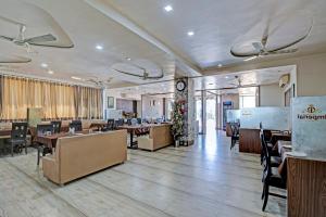 a restaurant with tables and chairs and a clock at Hotel O The Grand Imperial Restaurant & Hotel Dhuva Railway station in Morbi +38 photos