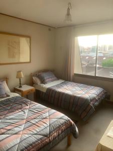 a hotel room with two beds and a window at Hostal Edificio Kuramochi in Temuco