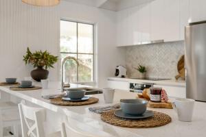 a kitchen with a table with cups and dishes on it at Backbeach House 1km to Beach in Blairgowrie