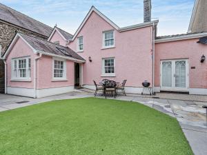 a patio with a table and chairs in front of a pink house at 3 bed in Aberaeron 86578 in Aberaeron