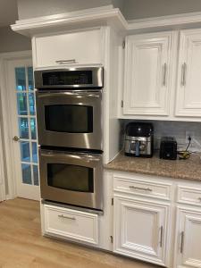 eine Küche mit weißen Schränken und einem Edelstahlofen in der Unterkunft Affordable 4 bedrooms home with a pool! in Houston