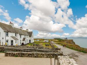 - une vue sur un village côtier avec des bâtiments et l'océan dans l'établissement 2 Bed in Rhossilli 89302, à Rhossili