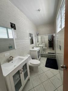 a bathroom with a toilet and two sinks and a shower at Enjoy Casa Brisas Del Mar in Maunabo, PR in Maunabo