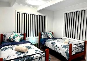 a bedroom with two beds and two windows at The Branch by the Basin Family Escape with Sunset Views in St Georges Basin