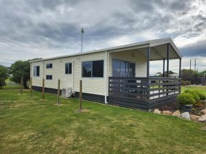 a white mobile home with a porch on a field at Seaspray Caravan Park in Seaspray