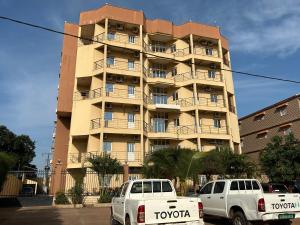 two cars parked in front of a tall building at 比绍民宿 in Bissau