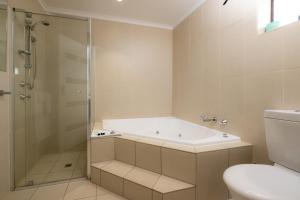 a bathroom with a tub and a shower and a toilet at Mick O'Sheas in Hackham +66 photos