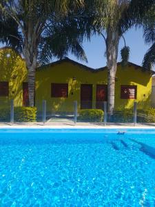 a yellow building with palm trees and a swimming pool at Cabañas Puertas del Sol in La Rioja +23 photos