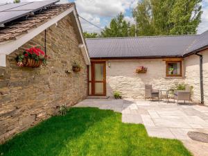 a stone house with a patio and a table and chairs at 1 Bed in Clyro 86975 in Clyro