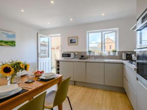 Una cocina con gabinetes blancos y una mesa de madera. en 2 Bed in Mundesley 83314, en Mundesley