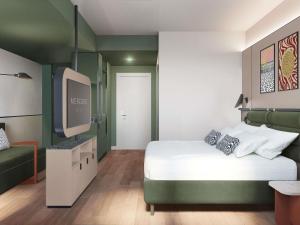 アグラーテ・ブリアンツァにあるMercure Milano Agrate Brianzaのベッドとテレビがあるホテルの部屋