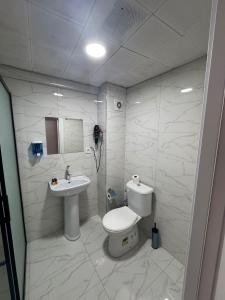 a white bathroom with a toilet and a sink at Old City Kadıköy Otel in Istanbul