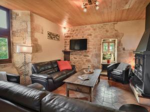 Una sala de estar con muebles de cuero y chimenea. en La Roque Haute, en Salles-de-Belvès
