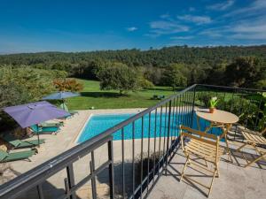 Un balcón con mesa y sillas y una piscina. en La Roque Haute, en Salles-de-Belvès