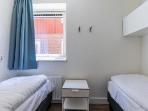 two beds in a small room with a window at Assum Great in Uitgeest