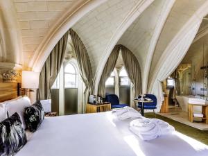 a bedroom with a large white bed with arched ceilings at Mercure Poitiers Centre in Poitiers +109 photos