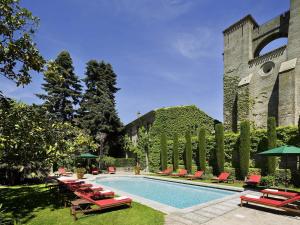 a swimming pool with red chairs and a building at Hotel de la Cité Carcassonne - MGallery Collection in Carcassonne