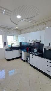 a large kitchen with white counters and appliances in a room at Appartement Calme et Jolie près de l'aéroport in Oulad Tayeb