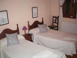 a bedroom with two beds and a table with a lamp at Hotel Rural Los Perales in San Vitero