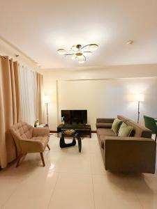 a living room with a couch and a chair at Staycacia Haven 2BR Condo Maple Acacia Taguig in Manila