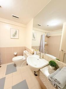 a bathroom with a white toilet and a sink at Staycacia Haven 2BR Condo Maple Acacia Taguig in Manila
