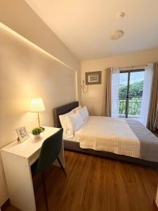 a bedroom with a bed and a desk and a window at Staycacia Haven 2BR Condo Maple Acacia Taguig in Manila