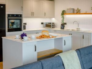 a kitchen with white cabinets and a counter with food on it at 3 bed property in Holsworthy 90721 in Holsworthy +22 photos