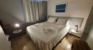 Un dormitorio con una cama blanca con dos lámparas. en Flat a 450 metros do centro - Praia da Pipa, en Pipa