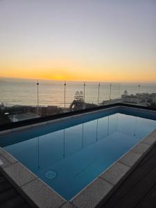a swimming pool with a view of the ocean at sunset at Arka Hotel in Viña del Mar