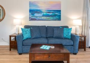 a living room with a blue couch and a table at Charming Beachside Garden Vistas in Wailea