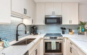 a kitchen with white cabinets and a stove and a microwave at Charming Beachside Garden Vistas in Wailea +41 photos