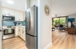 a kitchen with a stainless steel refrigerator and a living room at Charming Beachside Garden Vistas in Wailea