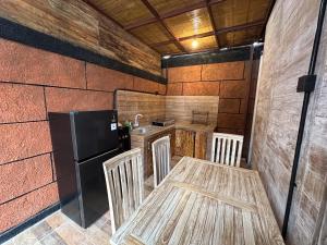 Una cocina con una mesa de madera y un refrigerador. en Joglo Silvi Gianyar singapadu, en Darmasaba