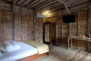 Un dormitorio con una cama en una pared de madera. en Joglo Silvi Gianyar singapadu, en Darmasaba