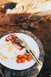 a plate of food with bacon and eggs and a knife and fork at Gabarraa Luxury Escape in Tenterfield +9 photos