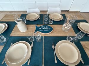 einen Tisch mit Tellern und Besteck auf einem blauen Tischtuch in der Unterkunft Les Terrasses du Phare, vue mer, 100m plage, pkg, terrasses, accès PMR in Berck-sur-Mer