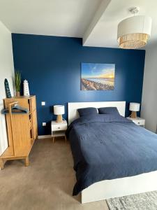 ein blaues Schlafzimmer mit einem Bett und einer blauen Wand in der Unterkunft Les Terrasses du Phare, vue mer, 100m plage, pkg, terrasses, accès PMR in Berck-sur-Mer